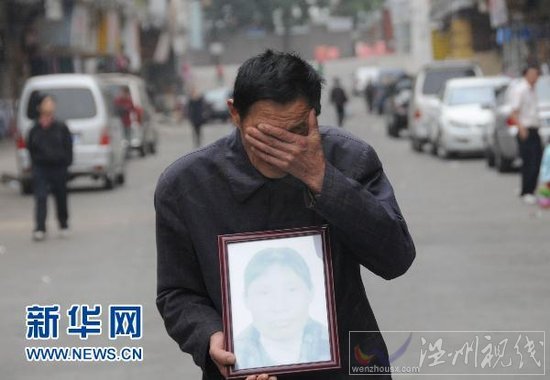 4月5日,在廣東省東莞市鳳崗鎮,肖國海捧著妻子吳喜英的遺像掩面哭泣。